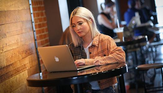 a woman sits at a counter looking at a laptop